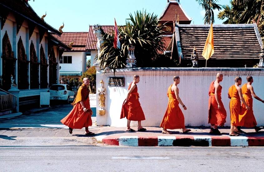 durante o dia, monges vestindo roupas laranjas, caminhando em uma das ruas de chiang mai tailândia