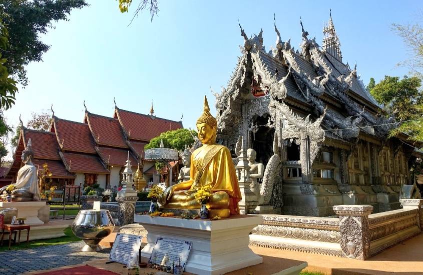 estátua de ouro de buda sentado, em frente a um dos templos em chiang mai, durante o dia