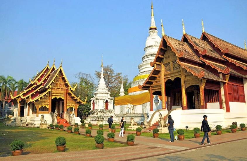 pessoas caminhando em frente a templos tailandeses, durante o dia