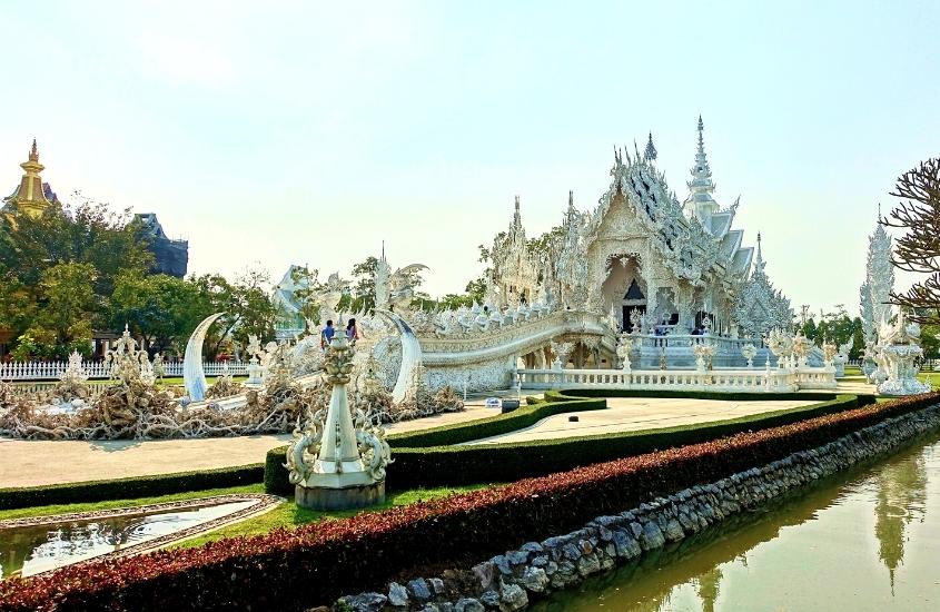 durante o dia, lago em frente a construção branca onde funciona um templo, em chiang mai
