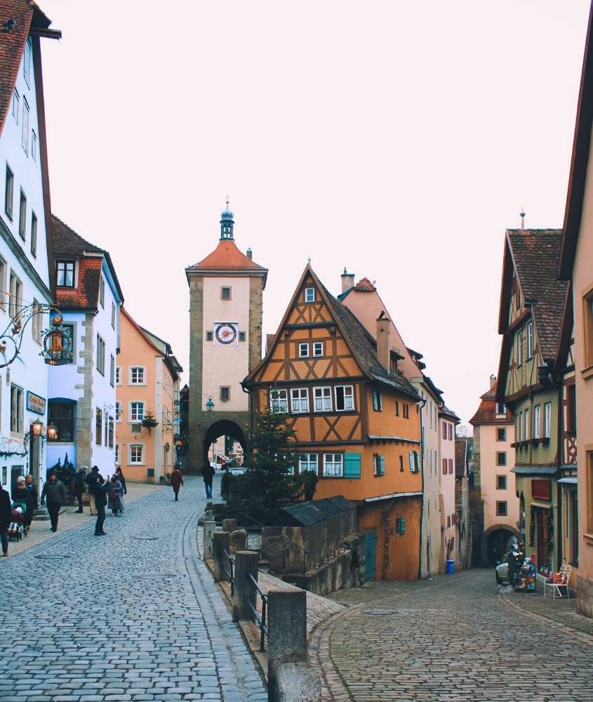 pessoas caminhando em meio a casas medievais coloridas, ao fazer turismo na alemanha, durante o dia