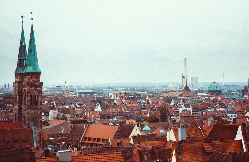 durante o dia, vista aérea de diversas casas com telhado laranja e castelo com telhado azul