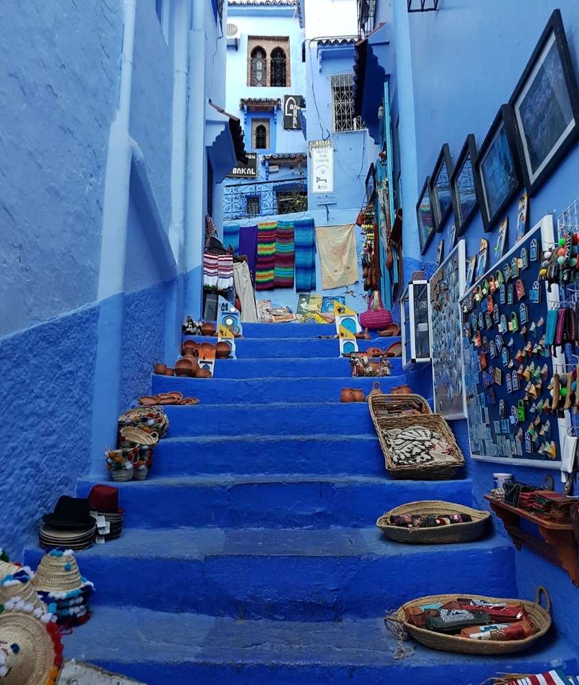 durante o dia, chapéus, objetos de cerâmicas, quadros e tecidos, em cima de escada azul