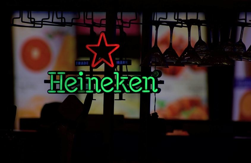 letreiro verde escrito 'heineken' pendurado em balcão de bar