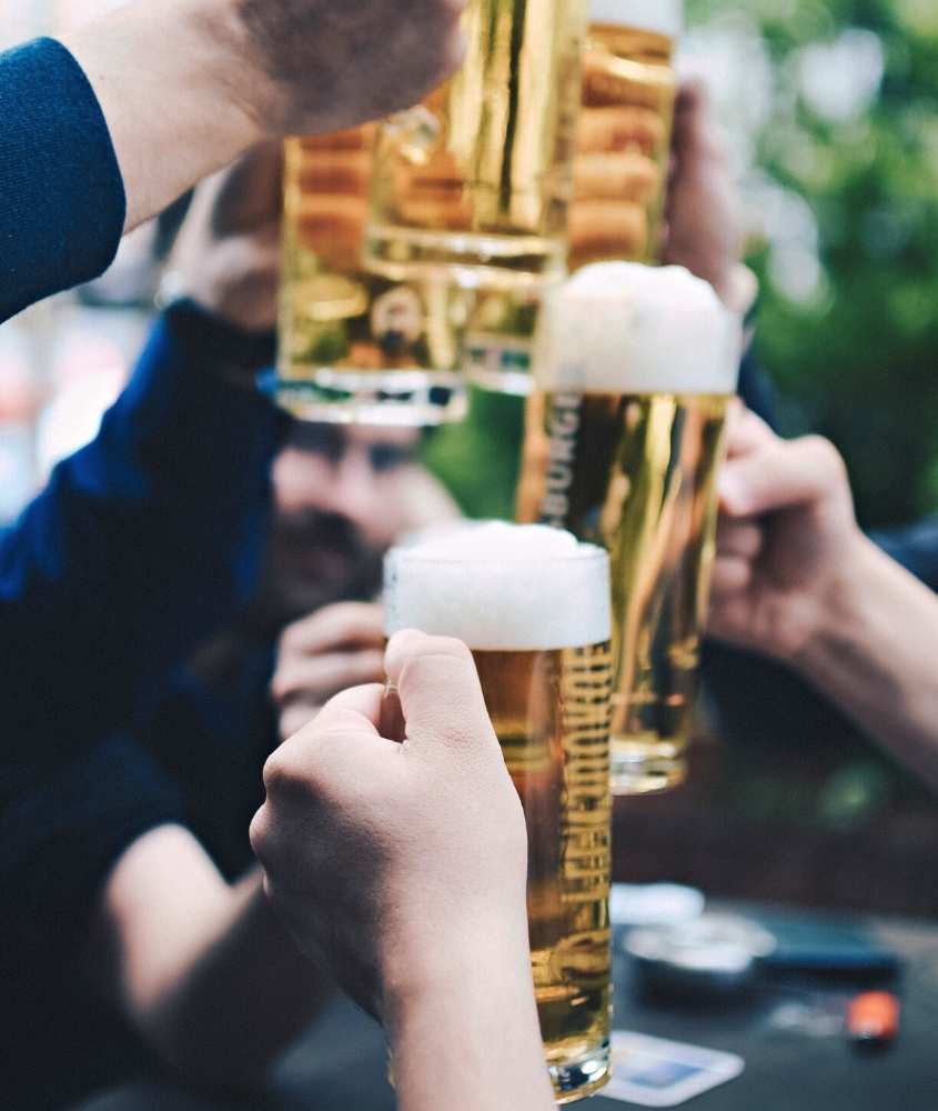 pessoas brindando segurando copo de vidro cheio de cerveja