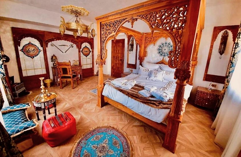 cama de casal, mesa, cadeira e sofá em quarto com decoração oriental