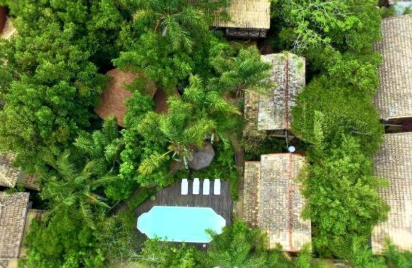 vista aérea, de piscina e construções com telhado de madeira, cercadas de árvores em um dos hoteis na guarda do embaú