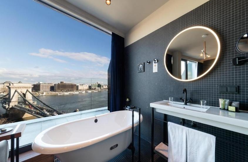 banheira de hidromassagem branca, em banheiro com ampla janela com vista para o rio danúbio, em um dos melhores hotéis em budapeste
