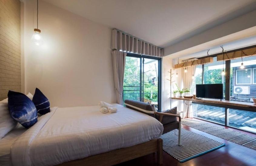 cama de casal e poltrona em suite com amplas janelas, durante o dia
