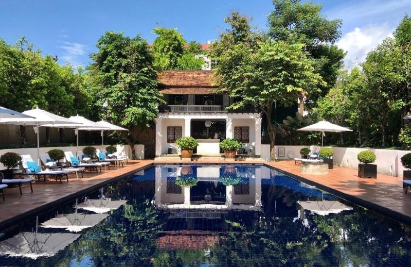 durante o dia, espreguiçadeiras ao redor de piscina de área de lazer arborizada de um dos melhores hotéis em chiang mai