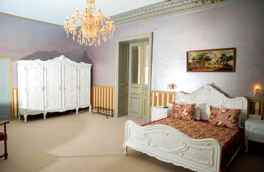guarda-roupa branco e cama de casal, em suite com lustre laranja em um dos hotéis em bucareste