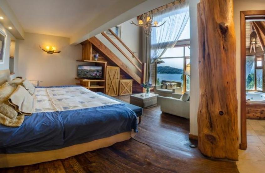 durante o dia, cama de casal, armário, sofás e banheira de hidromassagem em suite com vista para o lago em um dos hotéis em bariloche