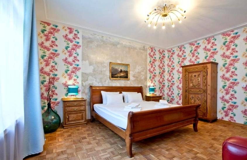 mesa de cabeceiras de madeira ao lado de cama de casal de madeira e guarda-roupa de madeira em suíte de hotel