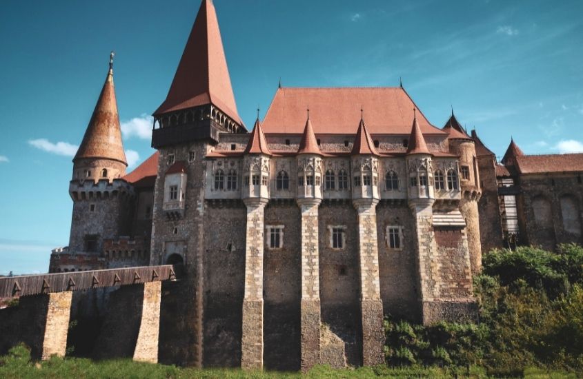 durante o dia, grande castelo com telhados marrons sob céu azul em uma das cidades da romenia