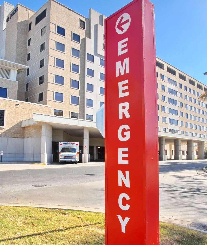 durante o dia, placa vermelha onde há escrito 'emergency' em frente a hospital