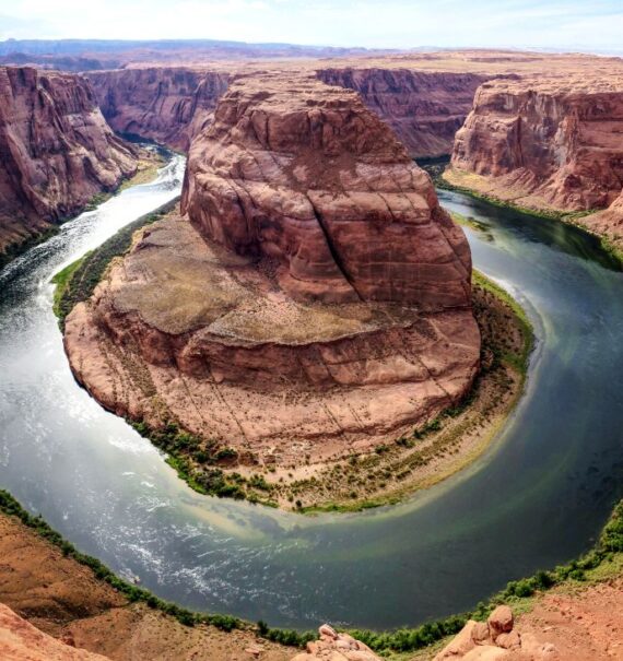 durante o dia, vista aérea de rio passando ao redor de grandes formações rochosas vermelhas de grand canyon, um dos principais pontos turísticos dos estados unidos
