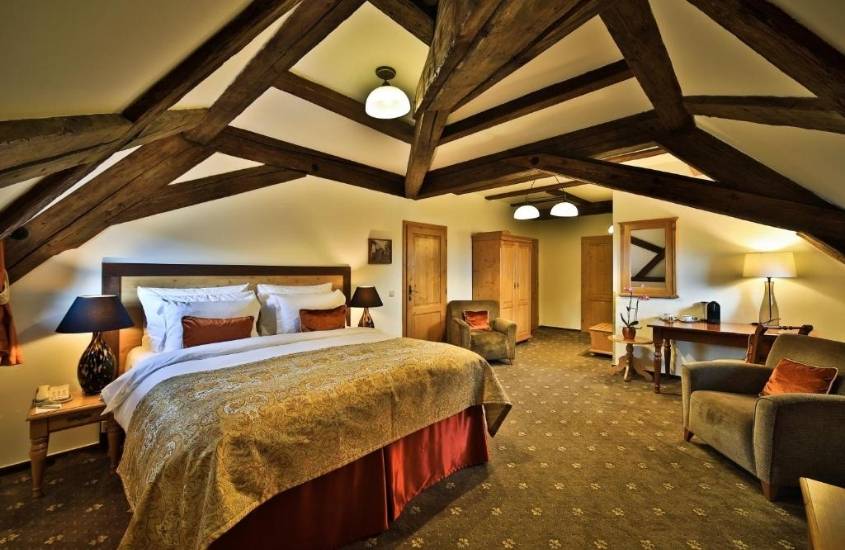cama de casal, poltronas e guarda-roupa de madeira em suíte de hotel em praga