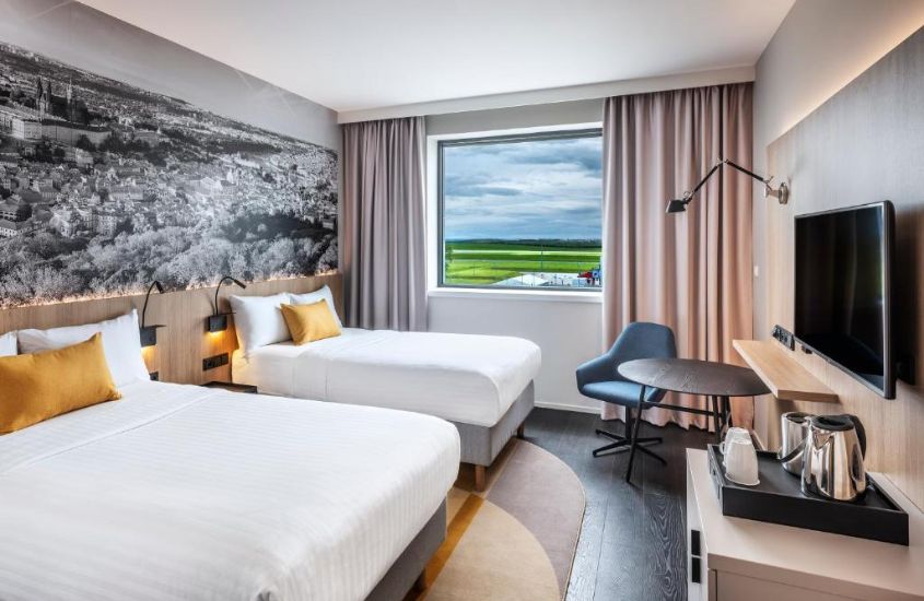 duas camas de casal e poltrona azul em suite com vista para a cidade em um dos hotéis em Praga próximo ao aeroporto