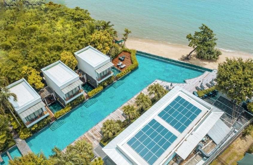 durante o dia, vista aérea de piscina, cercada de árvores em área de lazer com vista para o mar em um dos hotéis na Tailândia