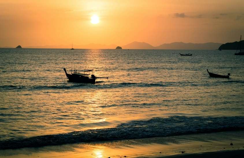 durante entardecer, silhueta de barco em mar de um dos melhores lugares na tailândia