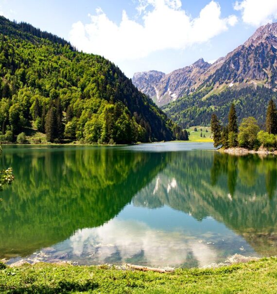 durante o dia, montanhas verdes refletindo em lago de umas cidades da suíça