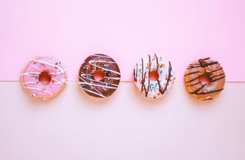 quatro donuts, sobremesa da culinária do Canadá, em cima de mesa branca e rosa
