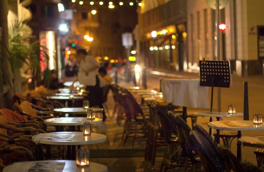 durante a noite, mesas e cadeiras ao ar livre em rua de budapeste, hungria