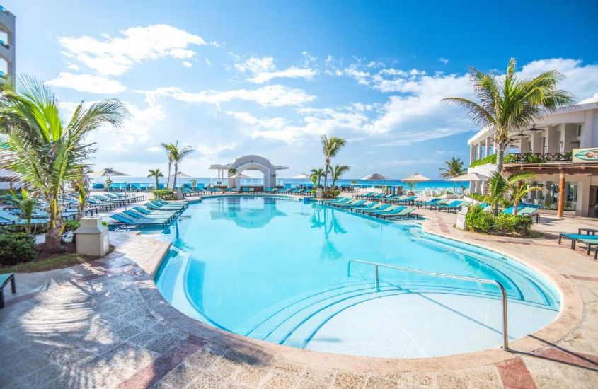 durante o dia, espreguiçadeiras ao redor de piscina com vista para uma das praias em cancún