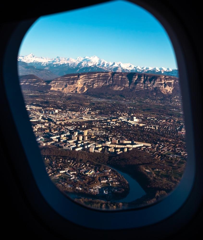 durante o dia, casas, prédios e montanhas vistos a partir de janela de avião em viagem para genebra