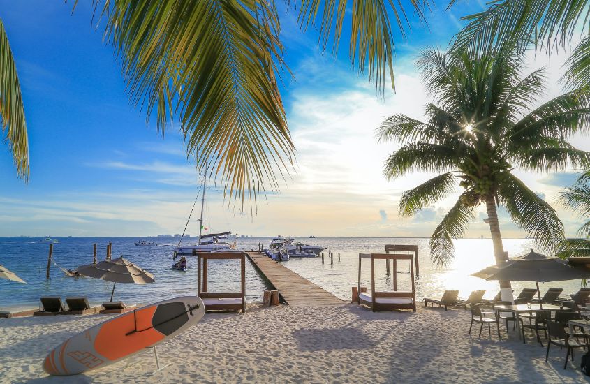 durante o dia prancha de surf, espreguiçadeiras, mesas, cadeiras e guarda-sol em areia em frente ao mar em Cancún México