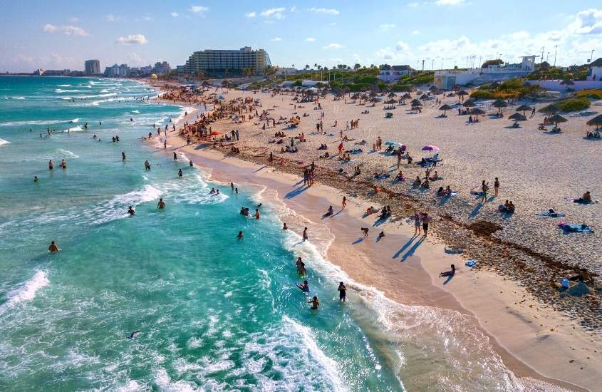 durante o dia, vista aérea de pessoas em areia e mar de punta cancun, um lugar onde ficar em Cancún