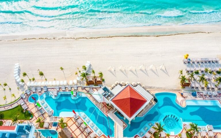 durante o dia, vista aérea de piscinas em área de lazer de um dos hotéis em cancun 5 estrelas com vista para o mar
