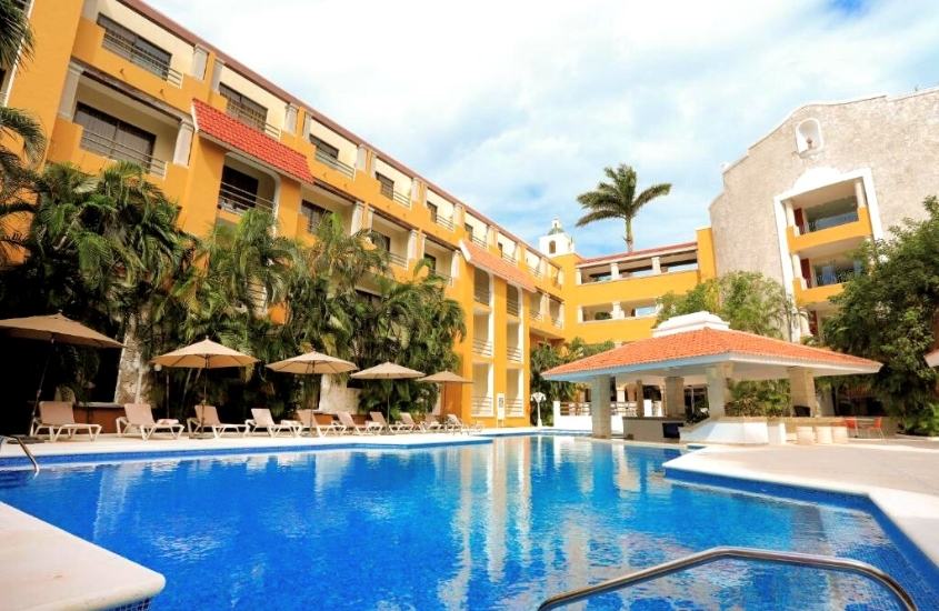 durante o dia, espreguiçadeiras e guarda-sóis em frente a piscina de um dos melhores hotéis em Cancún