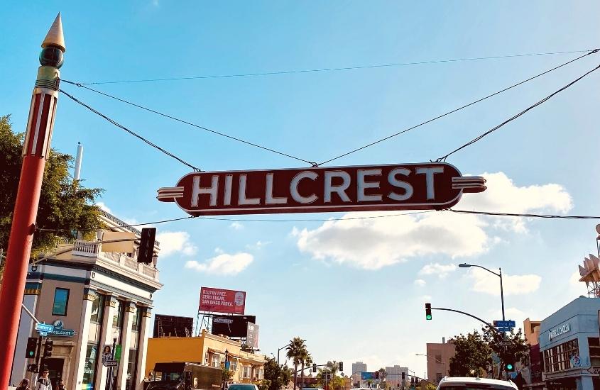 durante o dia, placa vermelha onde há escrito em branco 'hillcrest'', nome de bairro onde ficar em san diego califórnia