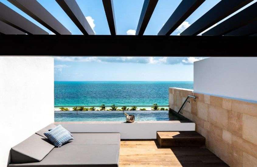 durante o dia, sofá em frente a piscina em varanda com piscina, em um hotel em cancún méxico com vista para o mar