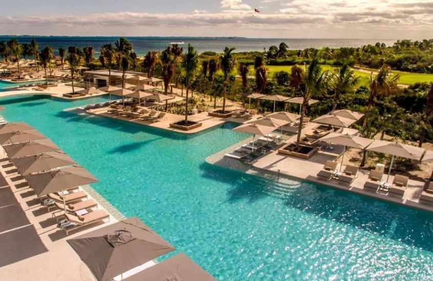 durante o dia, espreguiçadeiras e guarda-sóis ao redor de piscina em um dos melhores hoteis em cancun all inclusive