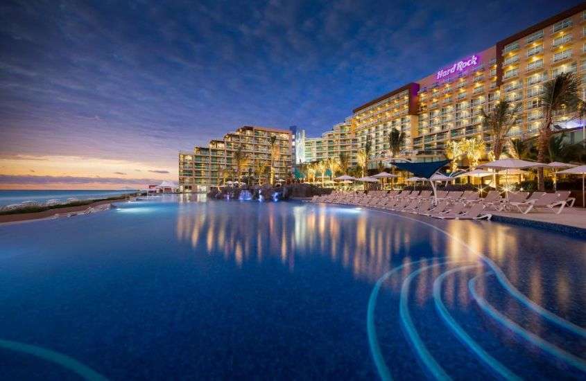 durante entardecer, espreguiçadeiras em frente a piscina em um dos melhores hoteis em cancun all inclusive