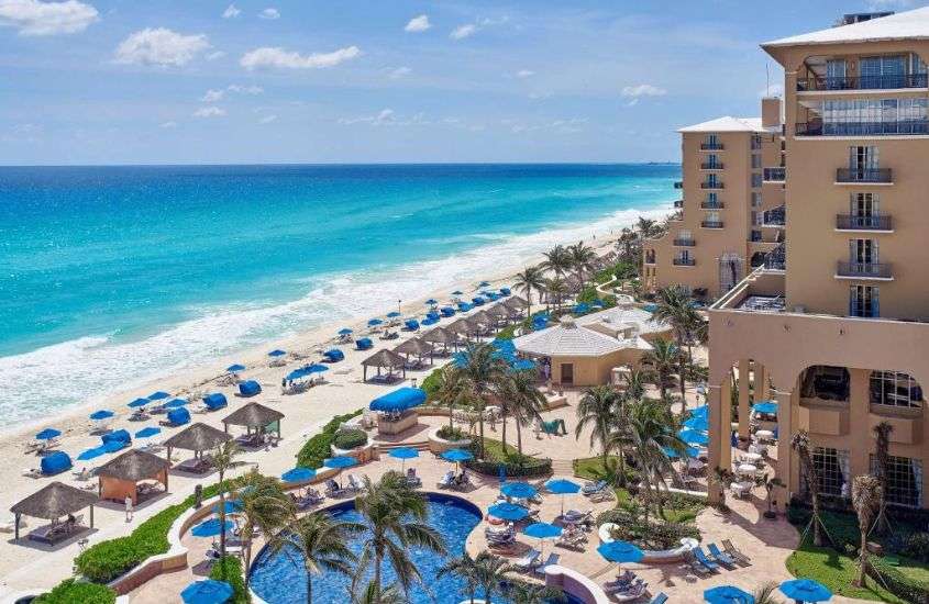 durante o dia, espreguiçadeiras e guarda-sóis ao redor de piscina em um hotel em cancun na zona hoteleira