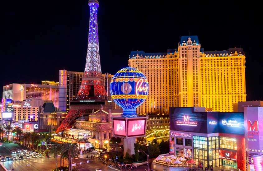 Durante a noite, Paris Las Vegas com prédios iluminados ao redor