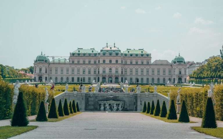 durante o dia, jardim em frente a grande palácio branco com telhado verde