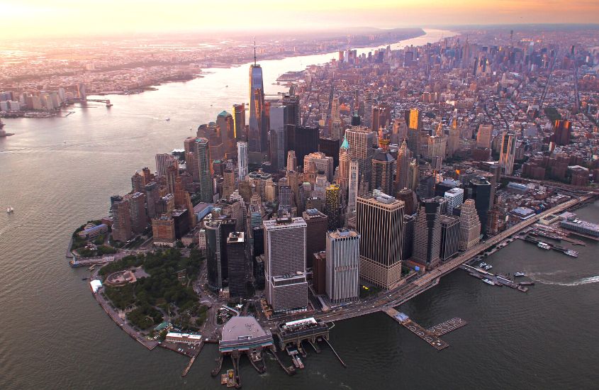 durante entardecer, vista aérea de prédios em ilha de manhattan, uma área onde ficar em nova york