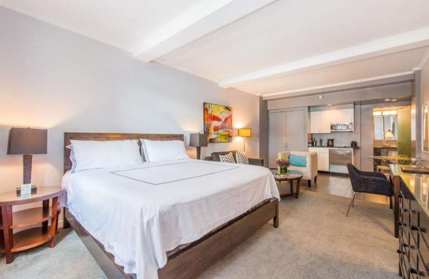 cama de casal, poltronas e cozinha compacta em um dos apartamentos em nova york para alugar