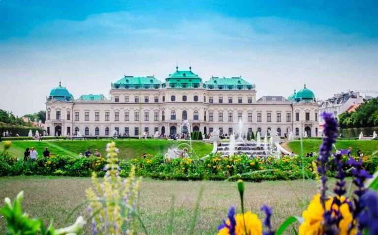 durante o dia, jardim em frente a grande palácio branco com telhado verde