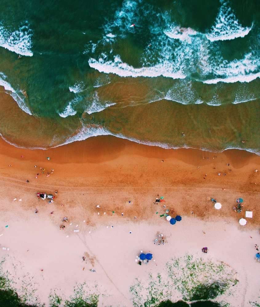 durante o dia, vista aérea de guarda-sóis e pessoas em areia em frente ao mar