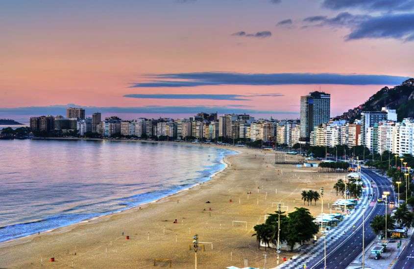durante entardecer, vista aérea de prédios em frente a praia de copacabana, lugar com uma das melhores festas de ano novo no rio de janeiro