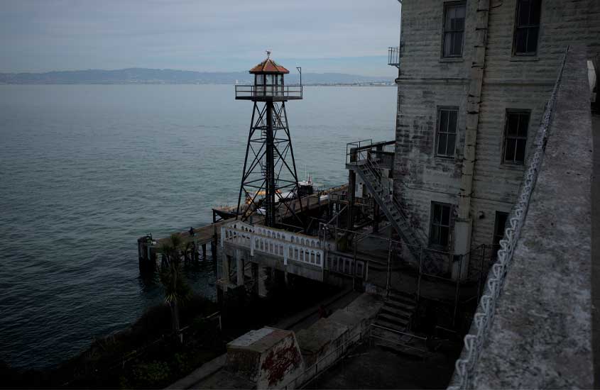 Em um dia nublado, ilha de Alcatraz com cadeia do lado e mar do outro