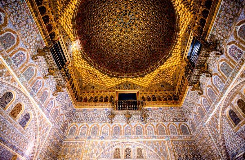 vista de baixo para cima, de interior de palácio, com cúpula dourada de real alcázar, um dos pontos turísticos de Sevilha