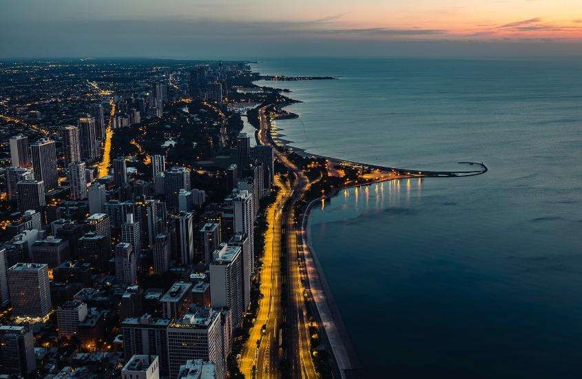 durante entardecer, vista aérea de prédios e ruas iluminadas em frente ao mar