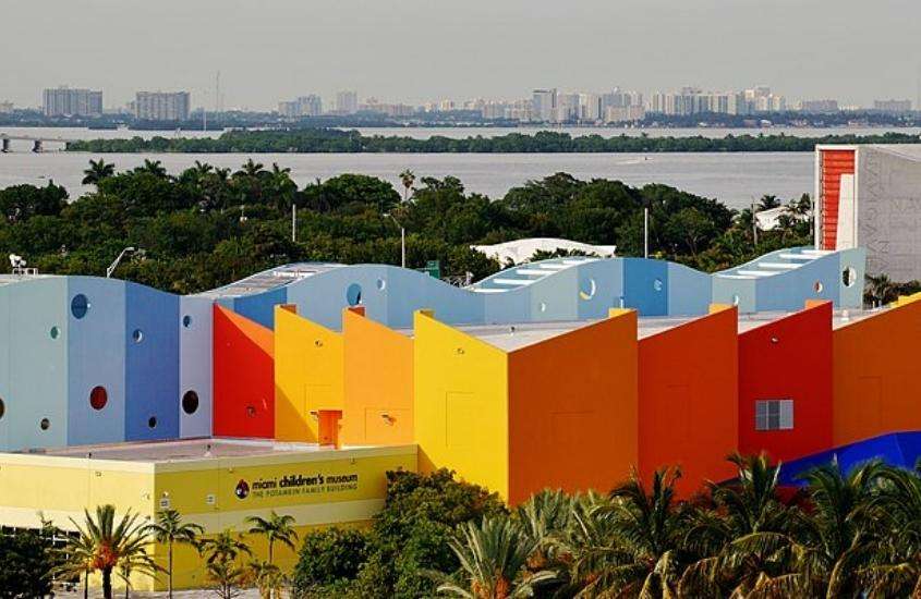 durante o dia, vista aérea de árvores em frente a construção azul, vermelha, laranja e amarela