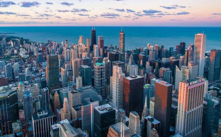durante entardecer, vista aérea de arranhas-céus e, ao fundo, mar em Chicago EUA